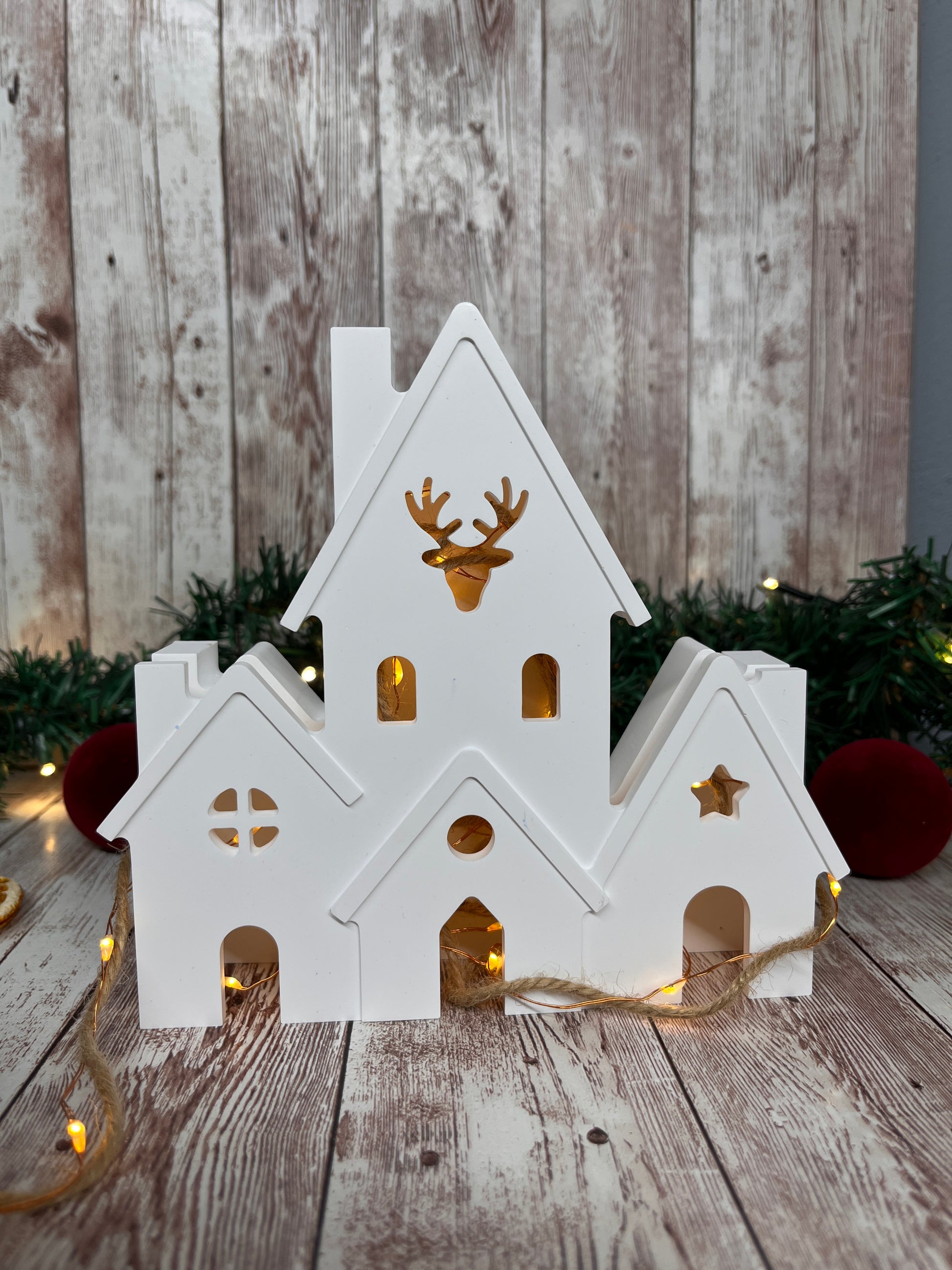 Weiße Lichthaeuser mit Elch in der Mitte. Man kann eine Lichterkette zum erleuchten des Keramikhauses hinzufügen. Keine Kerze