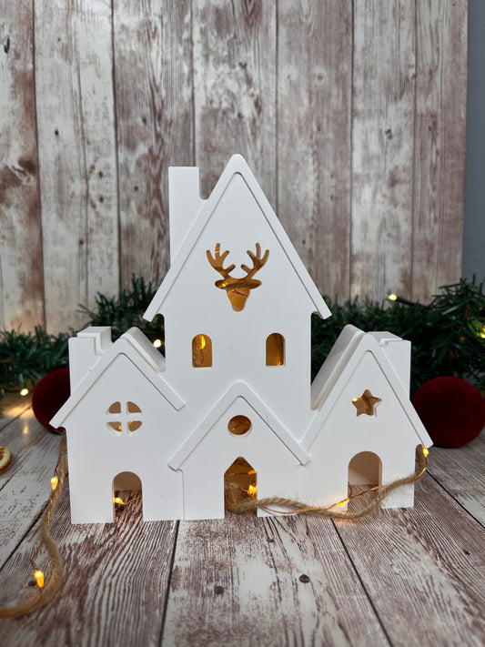 Weiße Lichthaeuser mit Elch in der Mitte. Man kann eine Lichterkette zum erleuchten des Keramikhauses hinzufügen. Keine Kerze